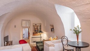 Un interior acogedor con techo de piedra, una mesa de comedor con sillas, una silla roja y un florero con flores.