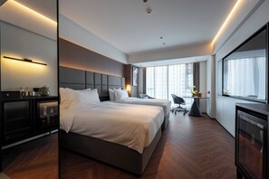 Una habitación de hotel moderna con dos camas, un escritorio, una silla y un ventanal grande.