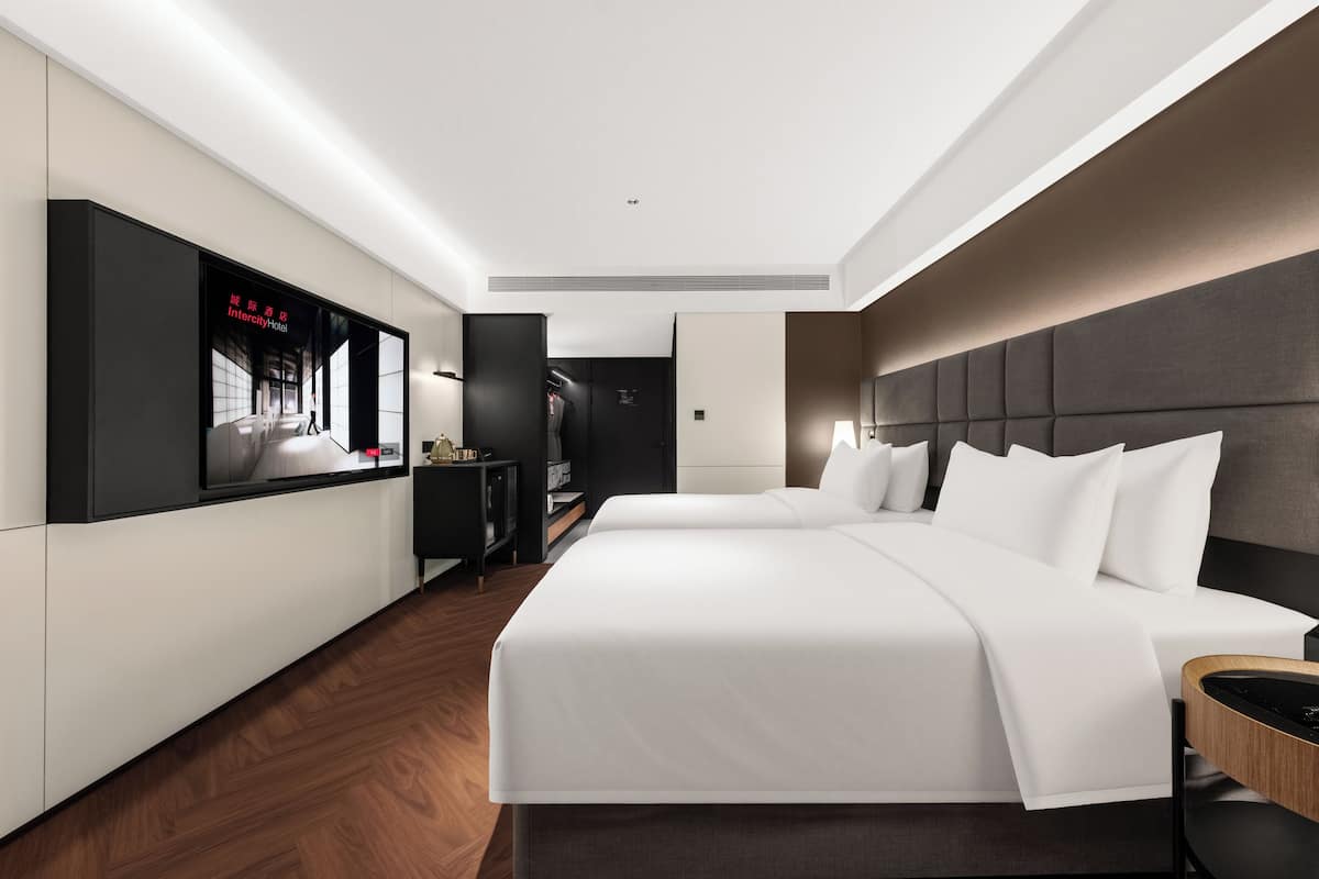 Ein modernes Hotelzimmer mit einem großen Bett, einem an der Wand montierten Fernseher und einem Kleiderschrank.