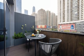 A balcony with a table, chairs, and potted plants. - Intercity Hotel Futian Convention (Shenzhen)