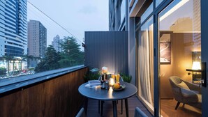 A balcony with a table set for two, a chair, and a view of the cityscape. - Intercity Hotel Futian Convention (Shenzhen)