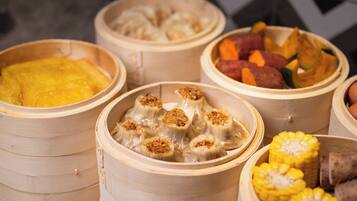 A variety of food items in bamboo steamers, including dumplings and corn.
