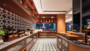 A buffet area with multiple serving stations, a patterned floor, and a kitchen in the background. - Intercity Hotel Futian Convention (Shenzhen)