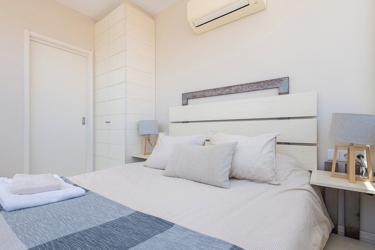 Een slaapkamer met een bed, nachtkastjes, een airconditioner en een wandplank.