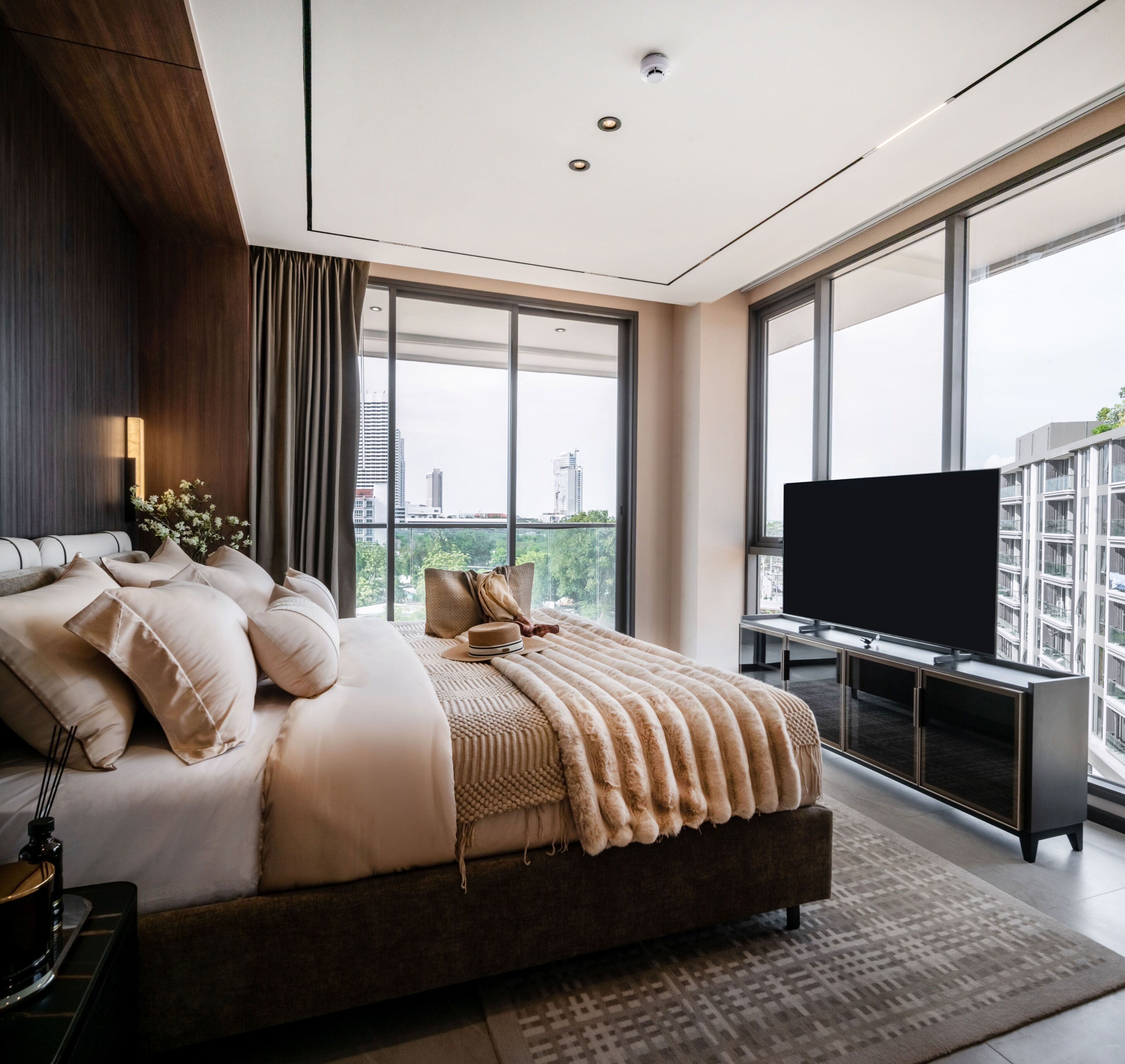 Un dormitorio moderno con una cama grande, televisión y vista a la ciudad.