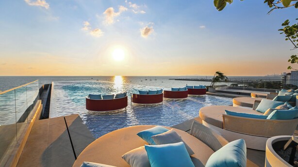 A poolside area with lounge chairs and a view of the ocean at sunset. - The Panora Estuaria Pattaya (Sattahip)
