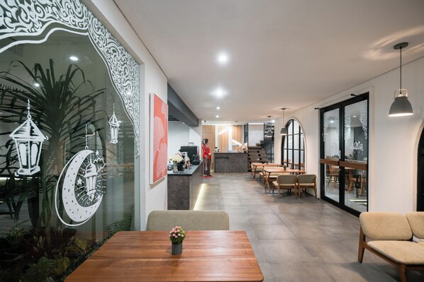 Un hall d’hôtel moderne comprenant un comptoir d’accueil, un espace salon et des œuvres d’art décoratives murales.
