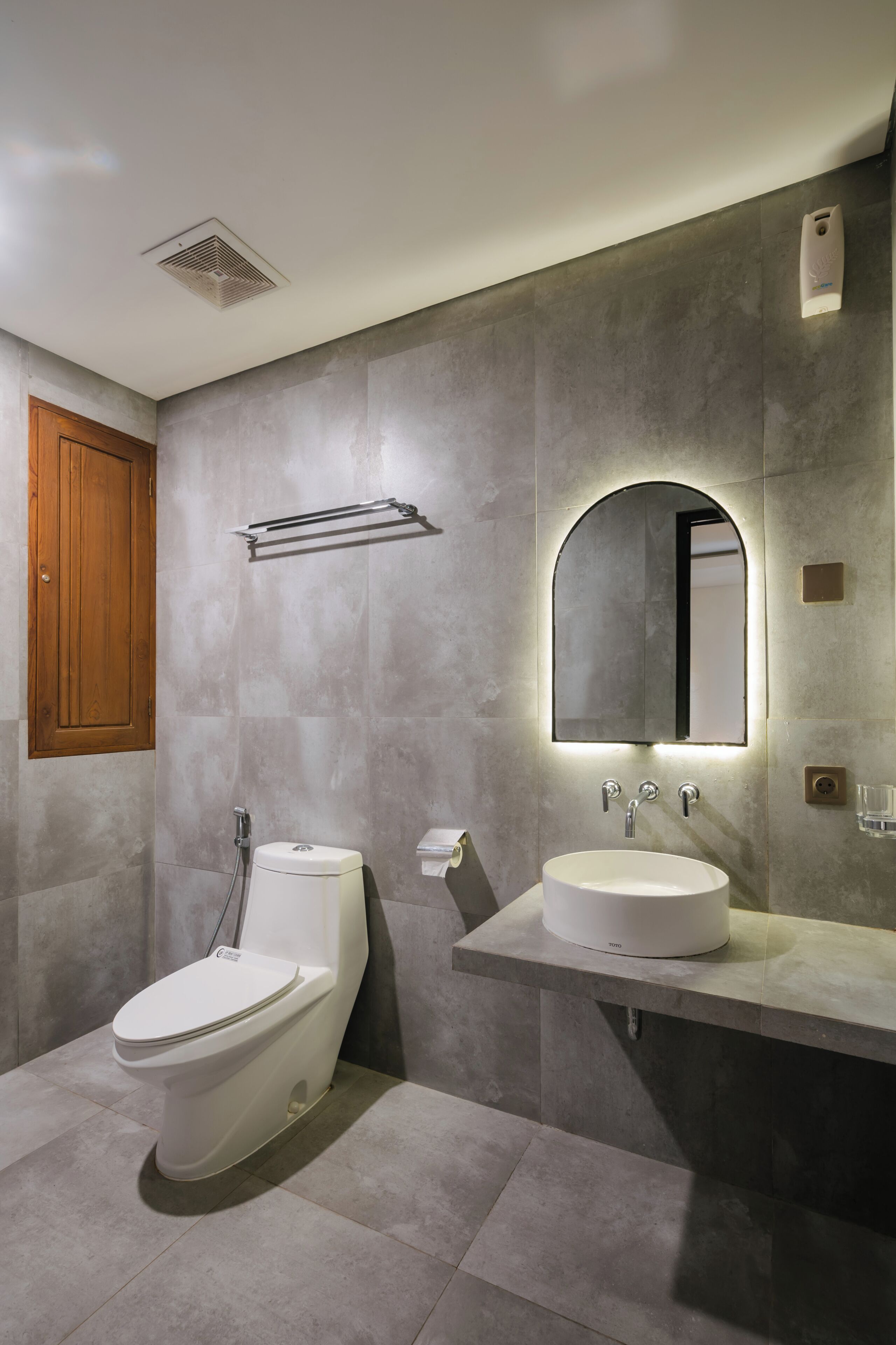 A modern bathroom with a toilet, sink, and mirror.