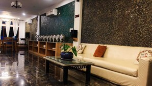 Et hotel lobby med et marmorgulv, en sofa, et sofabord med en plante, et barområde med glas og en dekorativ væg.