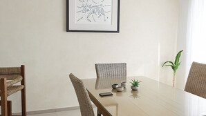 A dining area with a wooden table, wicker chairs, a framed picture, and a hanging light fixture. - Mareva Dreams · A safe and welcoming place (San Clemente de Lima)