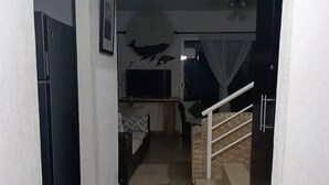 A hallway leading to a living area with a staircase, a refrigerator, a television, and a wall with animal silhouettes. - Mareva Dreams · A safe and welcoming place (San Clemente de Lima)