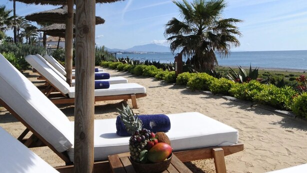 A beachside lounge area with sun loungers, a fruit bowl, and a view of the sea. - Relaxing Garden Apartment with Sea Views in Finca Cortesin Resort (Casares)