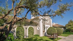 A building with arches, a hedge, and a sign. - Relaxing Garden Apartment with Sea Views in Finca Cortesin Resort (Casares)