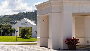 A building with 'FINCA CORTESIN' signage, a paved area with a potted plant, and a clear sky. - Relaxing Garden Apartment with Sea Views in Finca Cortesin Resort (Casares)