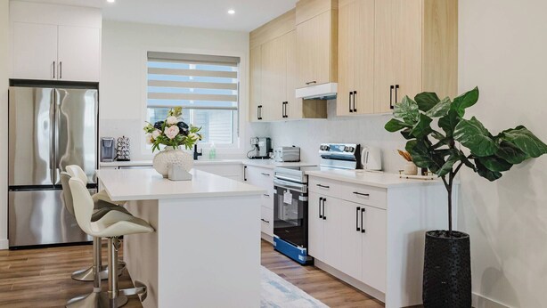 A modern kitchen with a central island, stainless steel appliances, and light wood cabinetry. - Brown Family Vacation Home - 4 Bedrooms- 3 baths (Leduc)