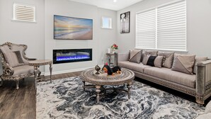A living room with a sofa, armchair, round coffee table, fireplace, and artwork on the walls. - A comfortable 3-bedroom home offers 5 beds and can accommodate up to 8 guests. (Rogers)