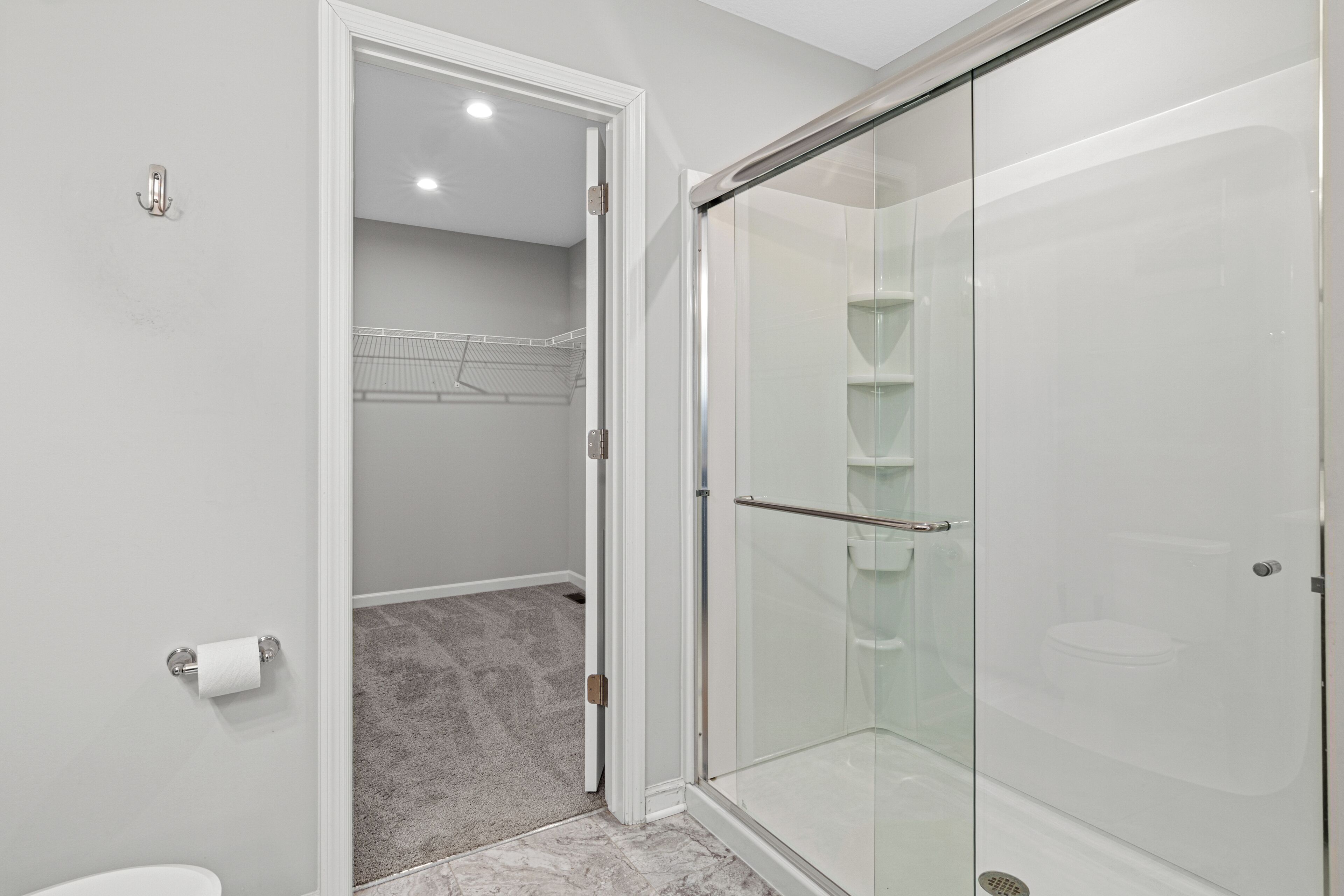 Un baño moderno con cabina de ducha de vidrio, inodoro y perchero para toallas.