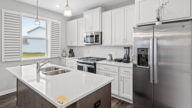 A modern kitchen with white cabinets, stainless steel appliances, and a large island with a sink. - A comfortable 3-bedroom home offers 5 beds and can accommodate up to 8 guests. (Rogers)
