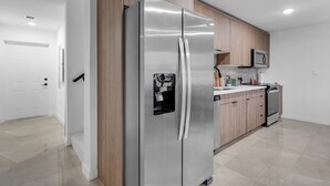 Een moderne keuken met roestvrijstalen apparatuur, houten kastjes en een witte deur.