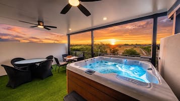 Un balcón con hidromasaje, mobiliario exterior y vistas al atardecer.
