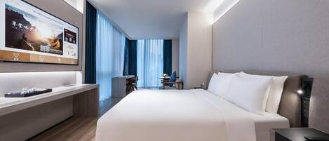 A modern hotel room with a large bed, a desk, a TV mounted on the wall, and a view of the outdoors through the window.