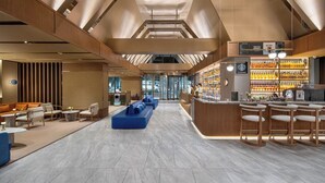 A modern hotel lobby with a central seating area, a bar, and a display of bottled beverages. - Orange Crystal Nanshan Science Park (Shenzhen)