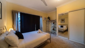 Une chambre à coucher comprenant un lit, une table de chevet, une commode, une armoire et un miroir.