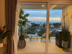 Uma varanda com vista para a cidade, um vaso de planta, uma mesa e duas cadeiras.