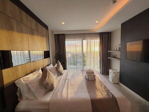 Une chambre d’hôtel avec un grand lit, une télévision, une vue sur la ville et un balcon.