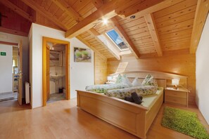 A bedroom with a wooden ceiling, a skylight, a bed with a green patterned bedspread, a bedside table with a lamp, and a green rug. - Apartment 'A' with Mountain View, Balcony and Wi-Fi (Moso in Passiria)