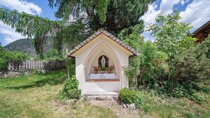 Una pequeña capilla con fachada blanca, techo puntiagudo y una estatua de la Virgen María.