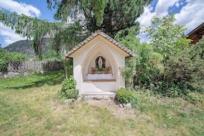 Una pequeña capilla con fachada blanca, techo puntiagudo y una estatua de la Virgen María.