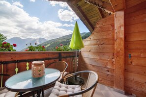 A wooden deck with a glass table and wicker chairs, overlooking a mountainous landscape. - Apartment 'A' with Mountain View, Balcony and Wi-Fi (Moso in Passiria)