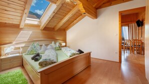 Un dormitorio de madera con tragaluz, cama, mesita de noche y alfombra verde.