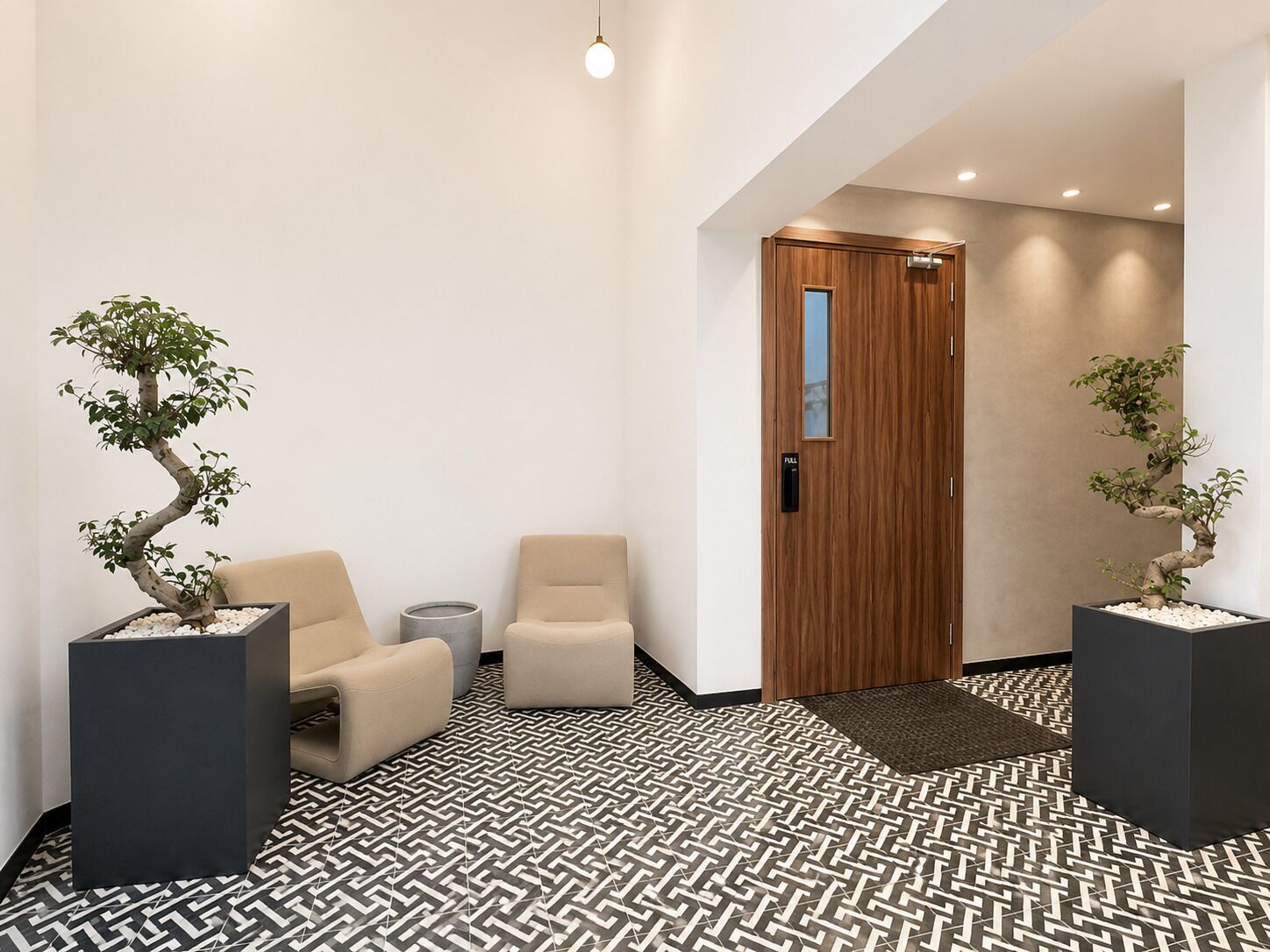 Een moderne lobby met twee bonsai-struiken in potten, beige fauteuils, een houten deur en vloerbedekking met een patroon.