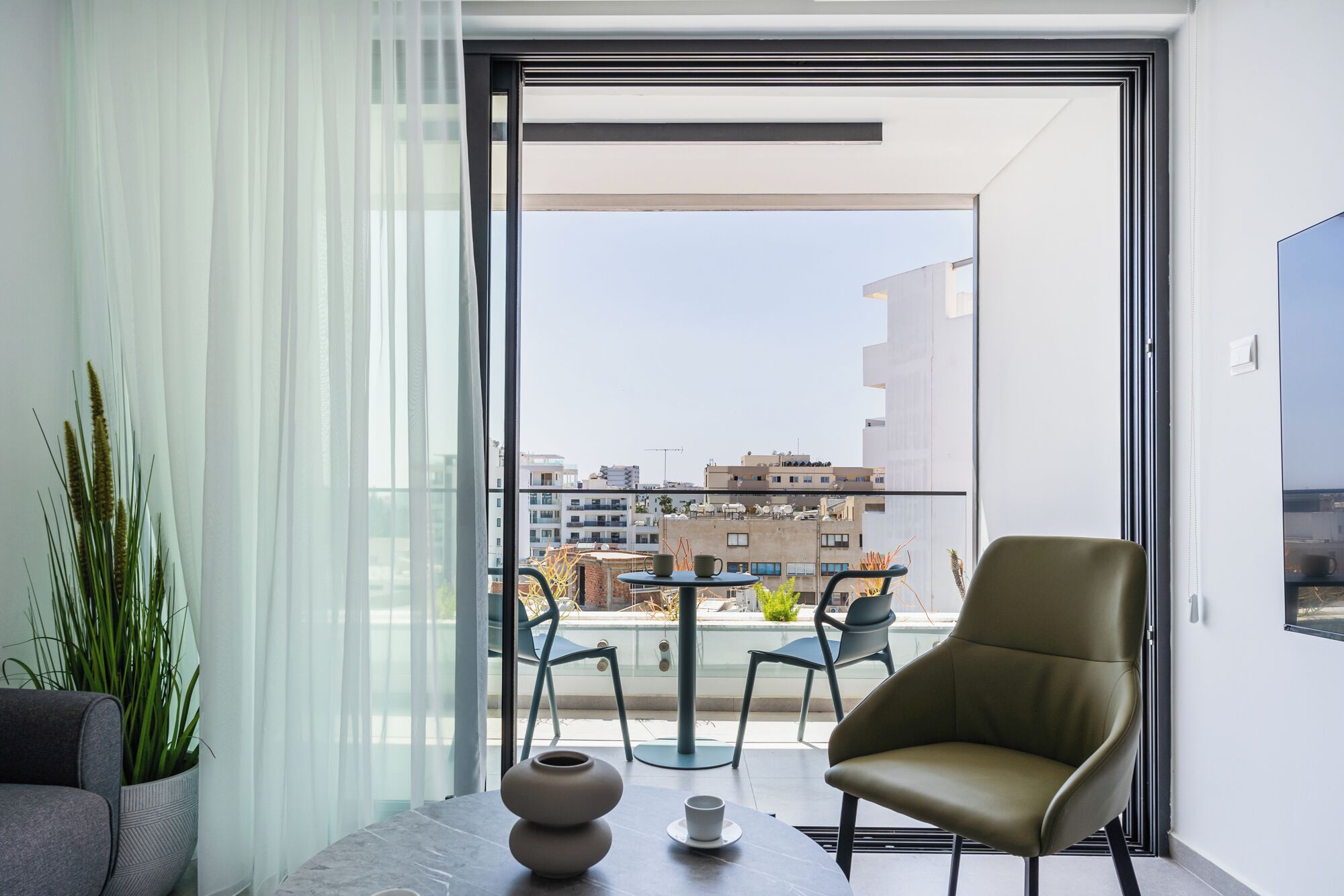 Un balcone moderno con una sedia, un tavolo e una pianta in vaso.
