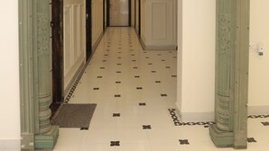 A hallway with a decorative archway, a patterned floor, and a hanging light fixture. - Krishneya Dham (Mathura)