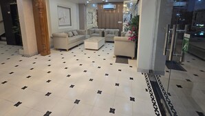 A spacious lobby with a chandelier, sofas, a coffee table, and a patterned floor. - Krishneya Dham (Mathura)