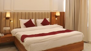 A bedroom with a bed, ceiling fan, nightstands, and a window with curtains. - Krishneya Dham (Mathura)