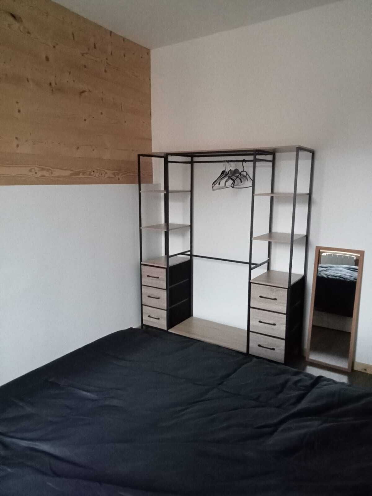Une chambre à coucher comprenant un lit, une armoire avec plusieurs tiroirs et un miroir.