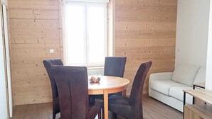 Ein Essbereich mit einem runden Tisch, vier Stühlen, einer Couch und Holzboden.