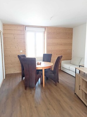 Ein Essbereich mit einem runden Tisch, vier Stühlen, einer Couch und Holzboden.
