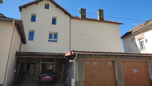 Ein zweistöckiges Gebäude mit Garage, ein Auto auf der Auffahrt und einem strahlend blauen Himmel.