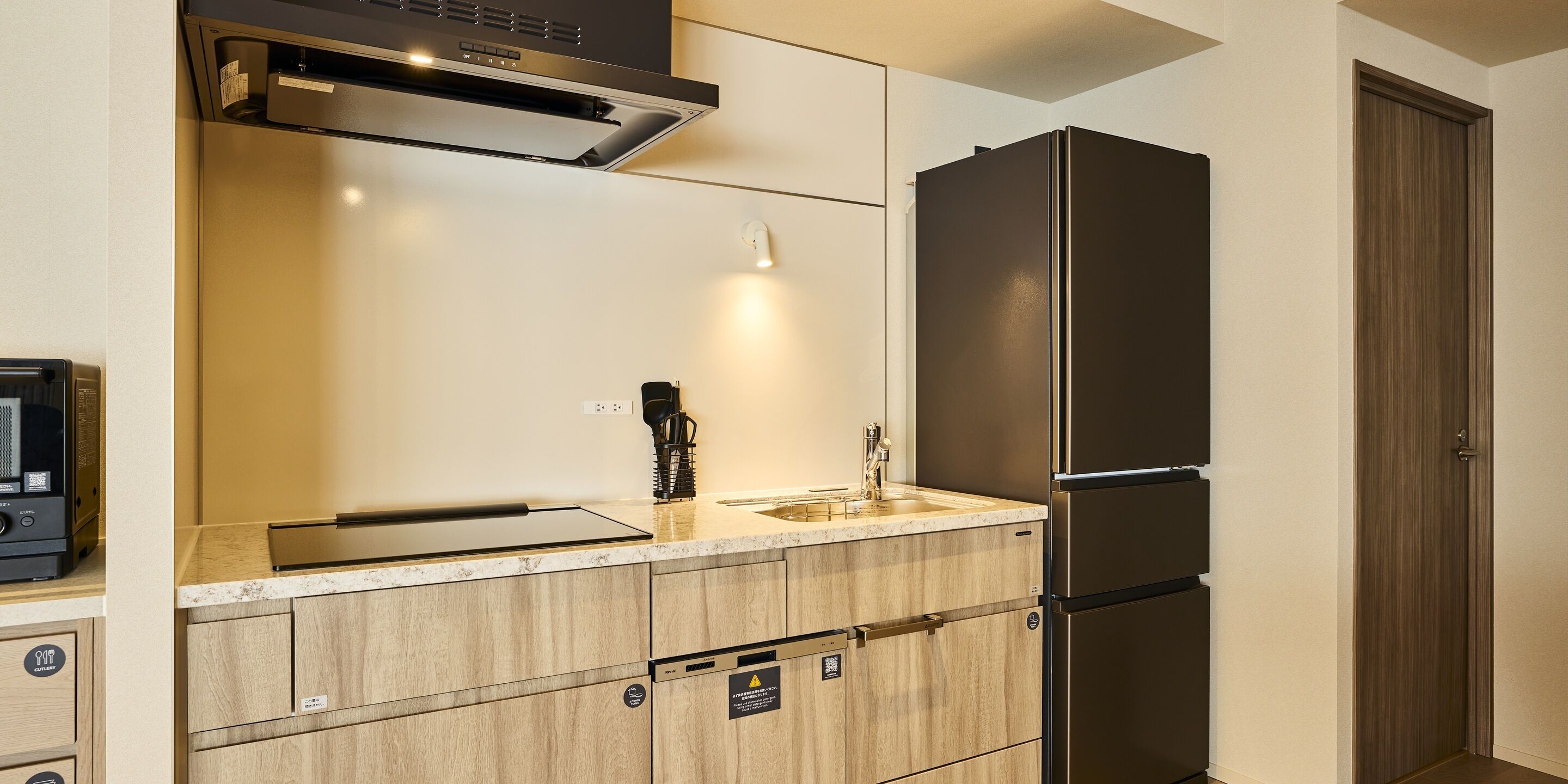 A kitchen with a stainless steel refrigerator, a built-in oven, and a microwave.