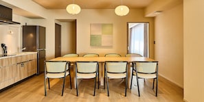 Une cuisine moderne avec une table et des chaises, un réfrigérateur et des luminaires suspendus.