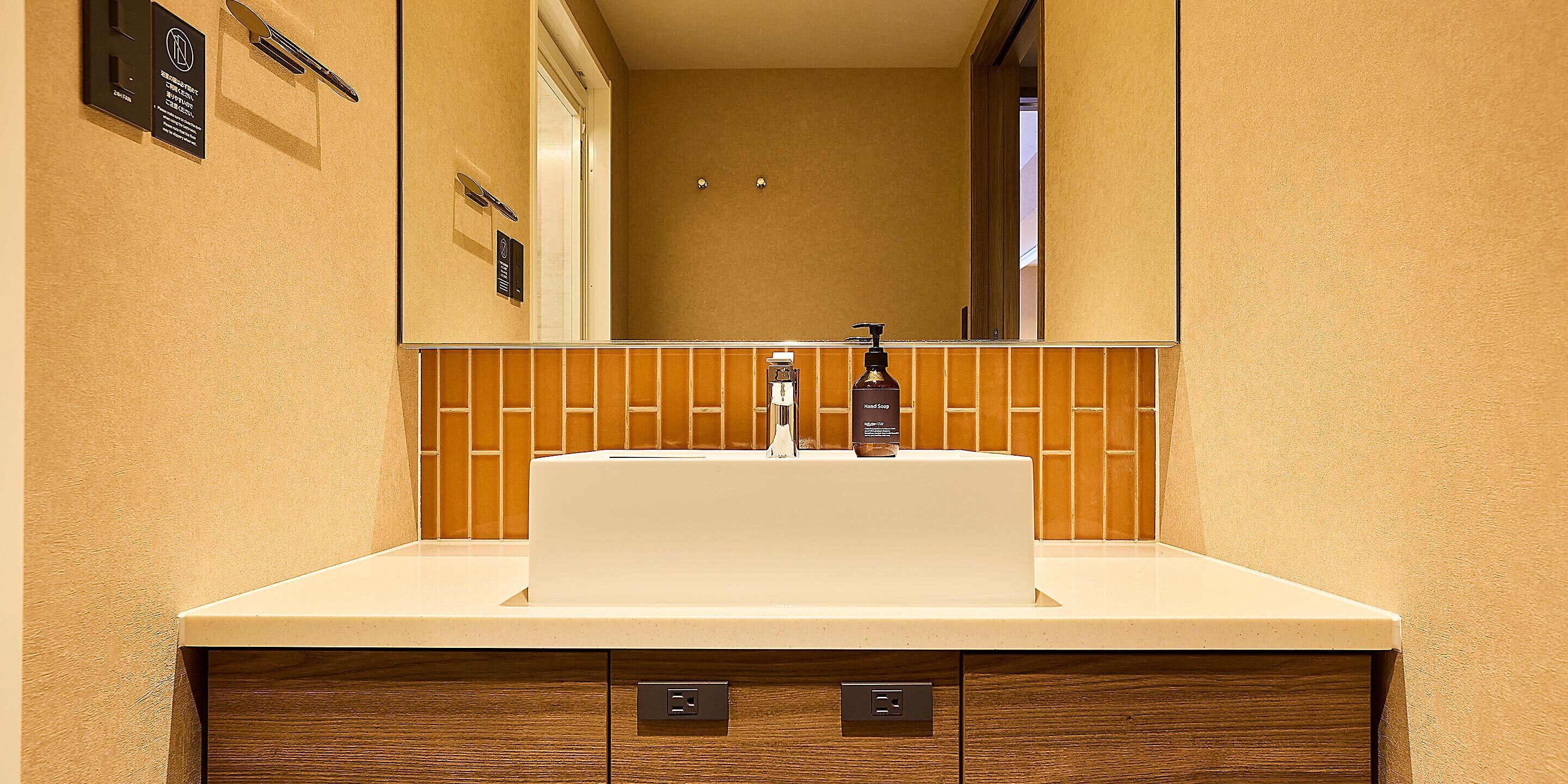 A bathroom with a white sink, a mirror above it, and a wooden cabinet below.