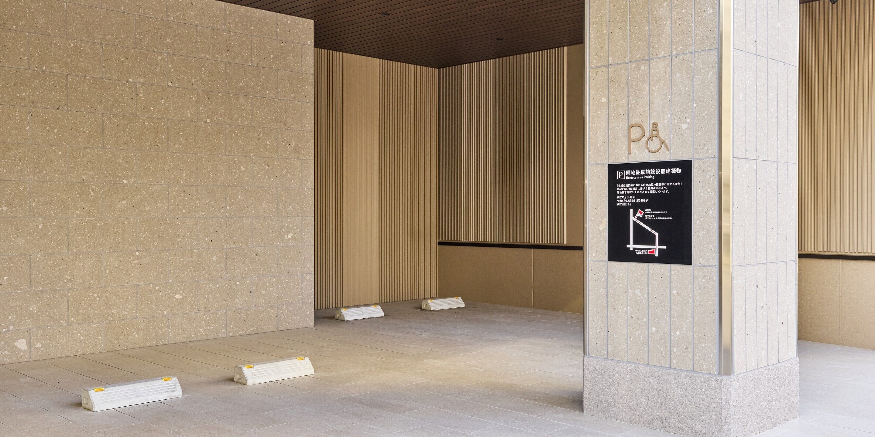 A modern interior with a tiled floor, a column with a sign, and a vertical wooden slat wall.