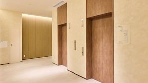 A corridor with two elevators, a wooden panel wall, and a floor plan sign. - Rakuten STAY Sapporo Nakajima Park (Sapporo)