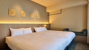 A hotel room with a large bed, bedside tables, wall-mounted lights, and a bench with cushions. - Rakuten STAY Sapporo Nakajima Park (Sapporo)