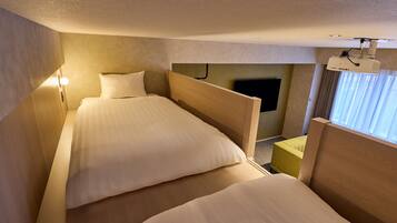 Ein Hotelzimmer mit zwei Betten, einem Fernseher und einem an der Decke befestigten Projektor.